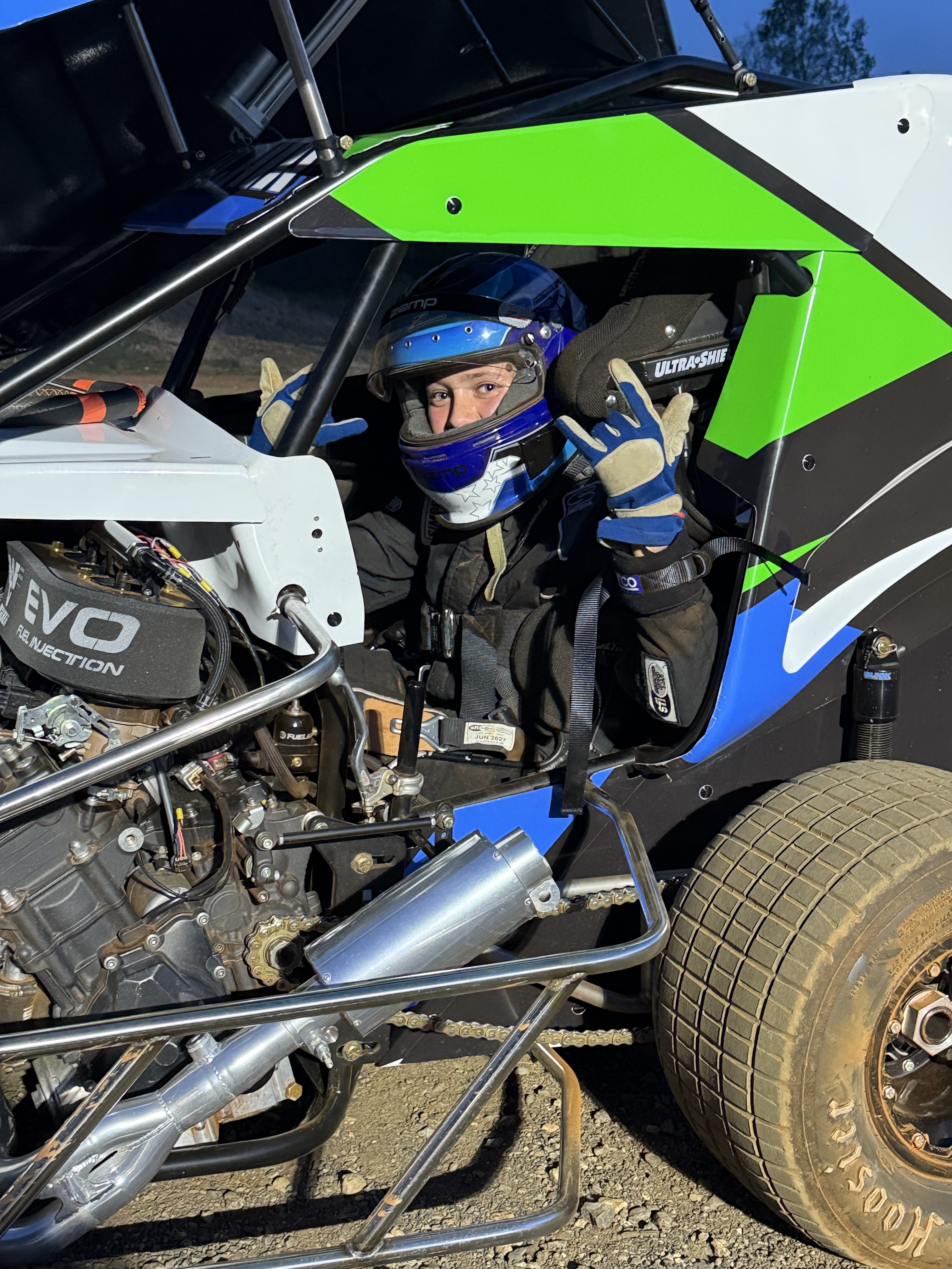 Driver sitting in sprint car cockpit wearing helmet